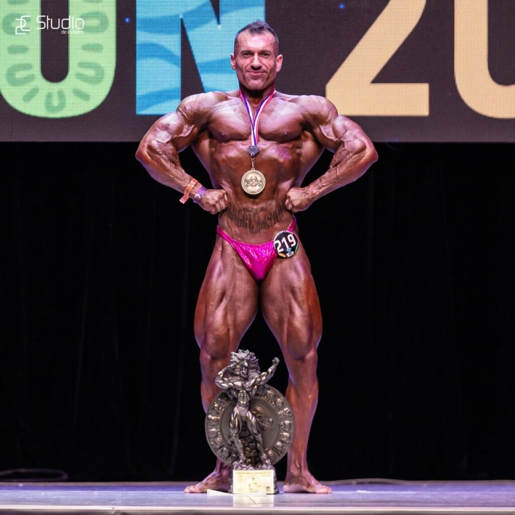 Alexis HC en tarima de culturismo con medalla y trofeo